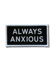 "Always Anxious" in white block text embroidered on black patch with white merrowed edge. Art by Print Ritual.