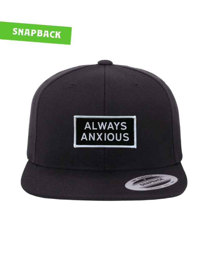 "Always Anxious" in white block text embroidered on black patch with white merrowed edge on a flat brim snap back.  Art by Print Ritual.
