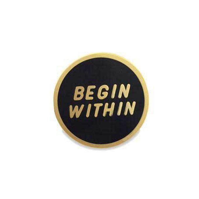 Black circle enamel pin with &quot;begin within&quot; in gold with gold border.