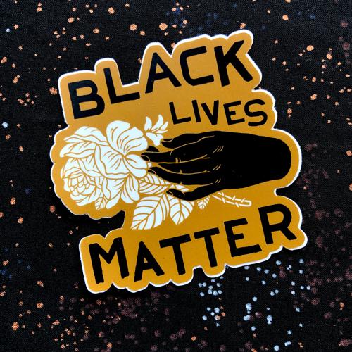 Vinyl sticker of black hand holding white peony with "Black Lives Matter" in Asymmetrical font on a warm mid yellow background.